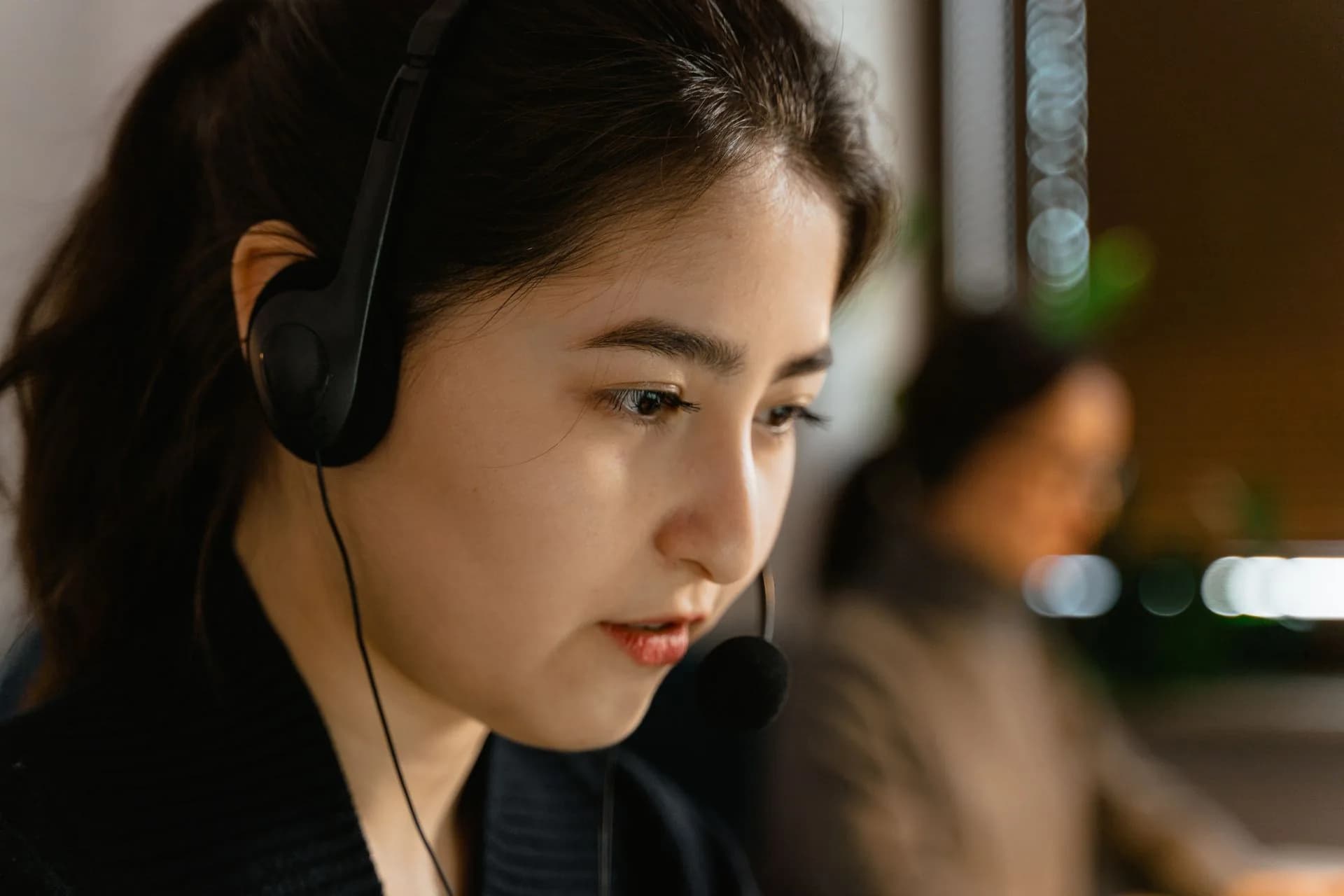 Asian customer service representative wearing a headset in an office